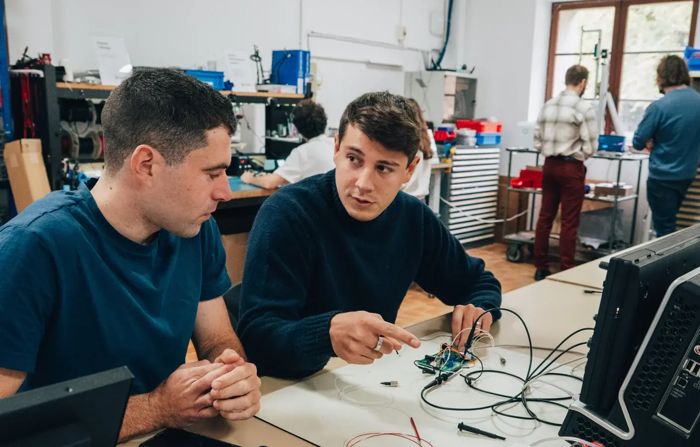 Deux ingénieurs d'Innowide analysent une carte électronique à l'atelier
